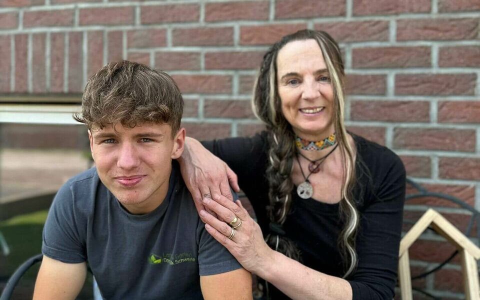 Gastmutter mit einem Jugendlichen auf einer Bank vor einem Haus