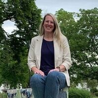 Betreutes Wohnen in Familien BWF Bethel.regional Hamm eine Frau sitzt auf einer Steinbank, im Hintergrund sind Bäume