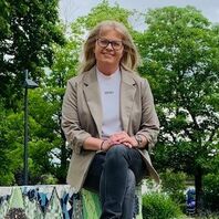 Betreutes Wohnen in Familien BWF Bethel.regional Hamm eine Frau sitzt auf einer Steinbank, im Hintergrund sind Bäume